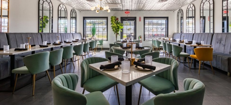 The Grand Room set for dinner, green velvet chairs and arched mirrors