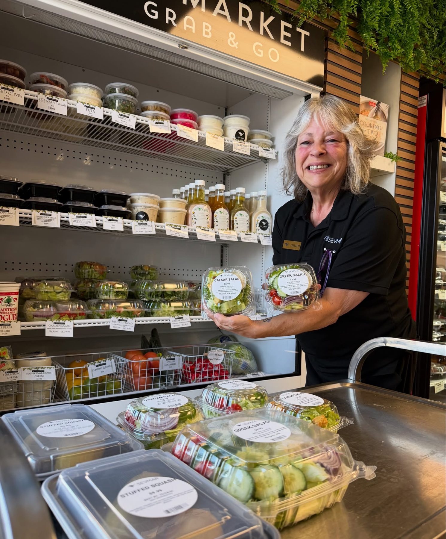 Janine holding Caesar and Greek salads to go