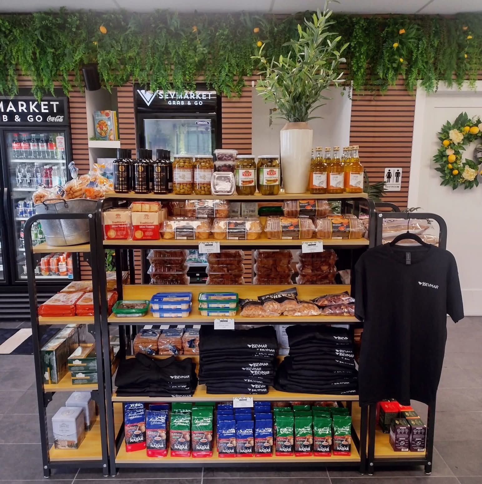Shelves with olives, cookies, coffee and SEVMAR tees